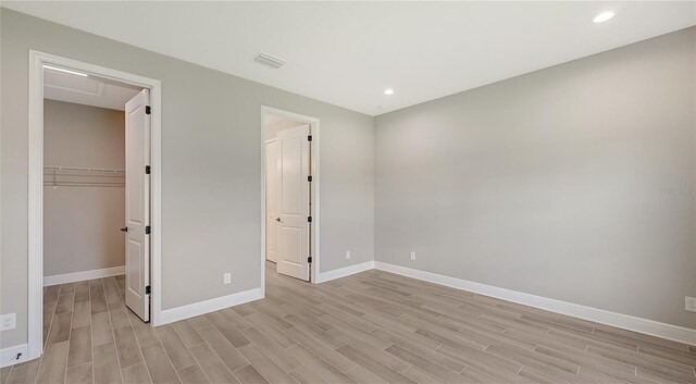 unfurnished bedroom featuring light hardwood / wood-style flooring, a walk in closet, and a closet