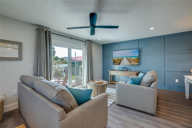 living room featuring ceiling fan, a textured ceiling, and light hardwood / wood-style flooring