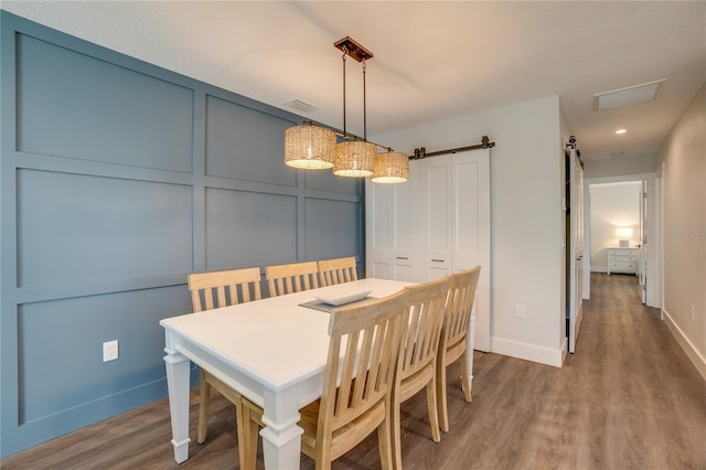 dining area with a barn door and hardwood / wood-style flooring