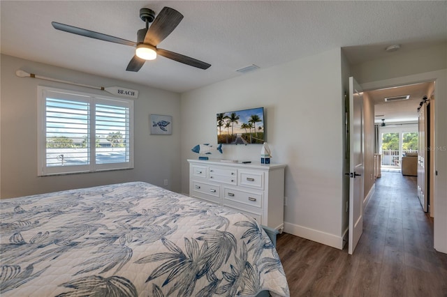 bedroom with a textured ceiling, ceiling fan, and dark wood-type flooring