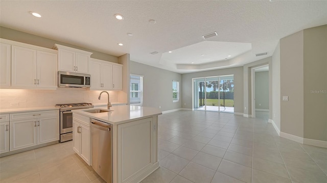 kitchen featuring sink, backsplash, white cabinetry, stainless steel appliances, and a kitchen island with sink