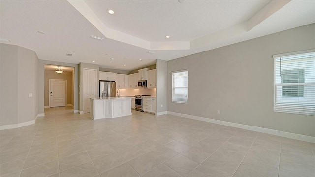 unfurnished living room with light tile patterned flooring, a tray ceiling, and a textured ceiling