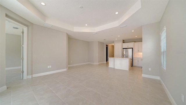 unfurnished living room with a tray ceiling and light tile patterned floors