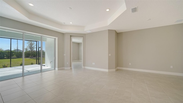 tiled empty room with a tray ceiling and a textured ceiling