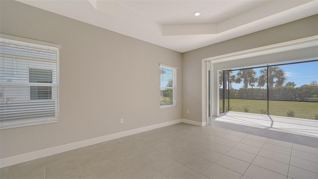 unfurnished room featuring light tile patterned floors and a tray ceiling