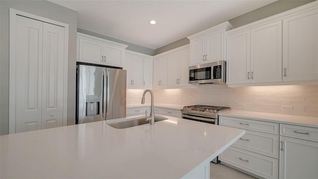 kitchen with sink, stainless steel appliances, white cabinetry, and backsplash