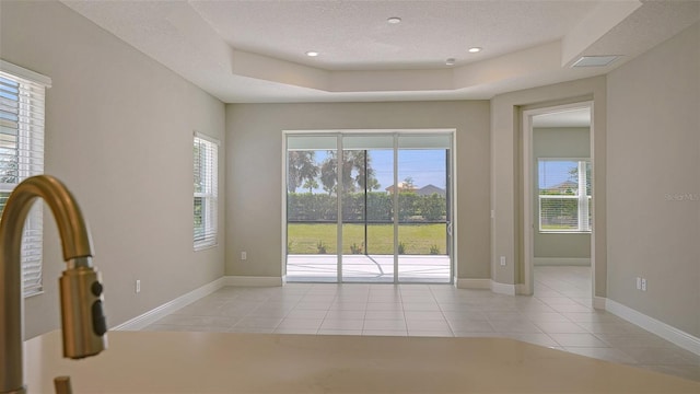 spare room with light tile patterned floors, a raised ceiling, and a textured ceiling