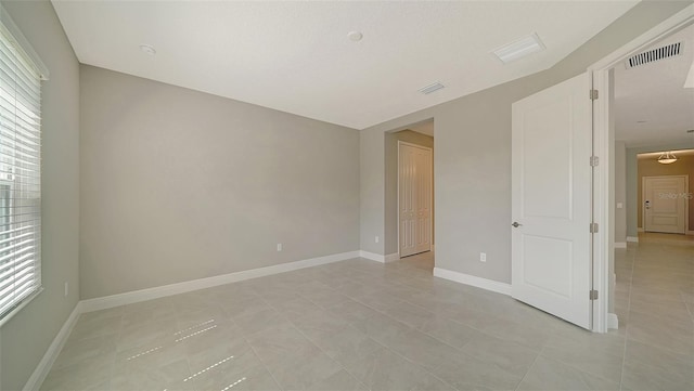 tiled spare room with a healthy amount of sunlight