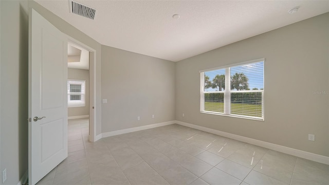 tiled empty room with a textured ceiling