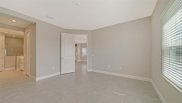 tiled spare room featuring a healthy amount of sunlight