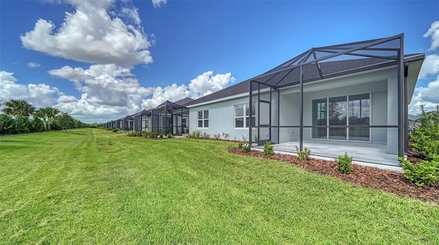 back of house with a patio, glass enclosure, and a lawn