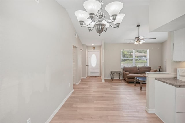 entryway with ceiling fan with notable chandelier, light hardwood / wood-style floors, and lofted ceiling