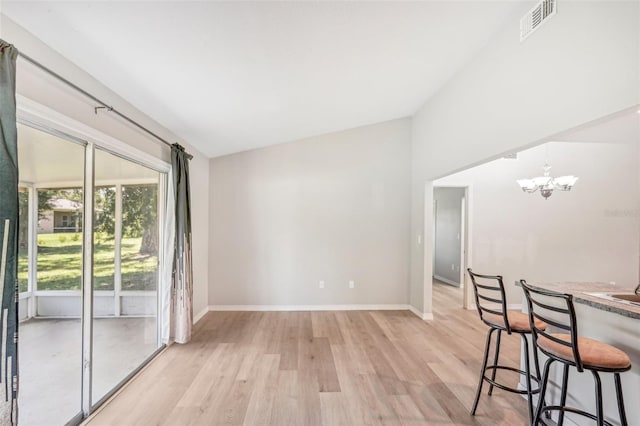 unfurnished dining area featuring light hardwood / wood-style flooring, lofted ceiling, and a notable chandelier