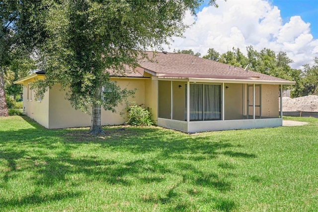 rear view of house featuring a lawn and a sunroom