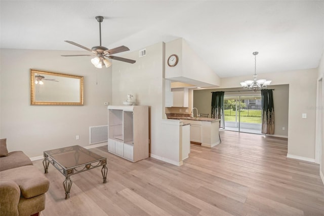 living room featuring ceiling fan with notable chandelier, light hardwood / wood-style flooring, lofted ceiling, and sink