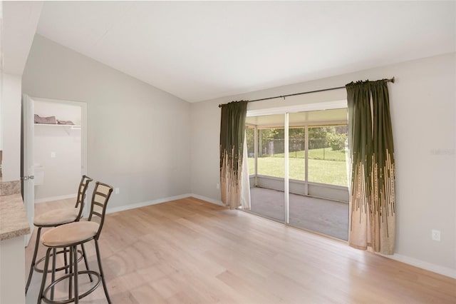 unfurnished dining area featuring light hardwood / wood-style floors and vaulted ceiling