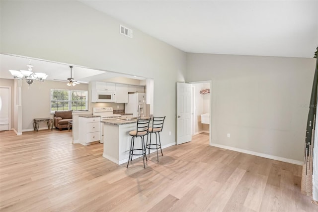 kitchen with white cabinets, light hardwood / wood-style floors, a kitchen bar, and white appliances