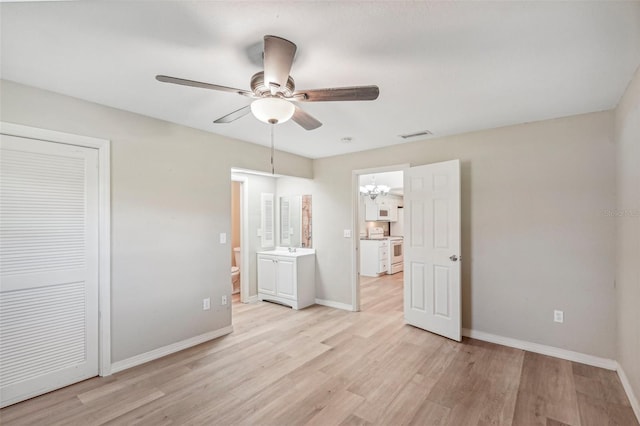 unfurnished bedroom with light wood-type flooring, ceiling fan with notable chandelier, ensuite bath, and a closet