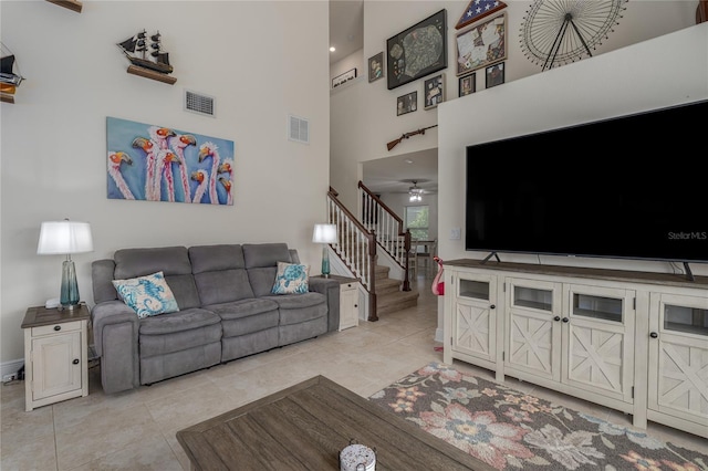 tiled living room featuring ceiling fan and a towering ceiling