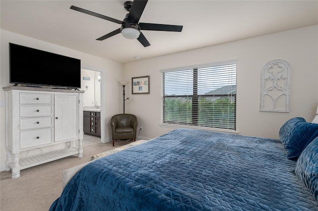 bedroom featuring ceiling fan, light colored carpet, and ensuite bathroom