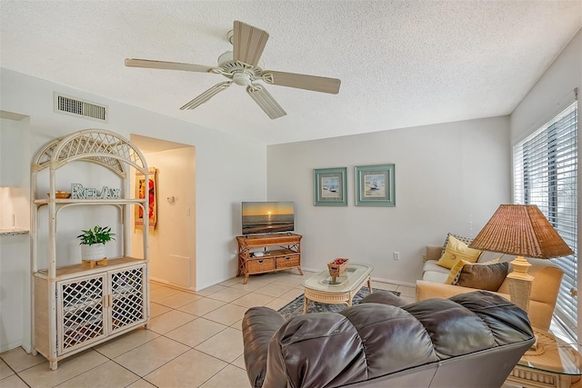 living room featuring a textured ceiling, ceiling fan, and light tile patterned floors