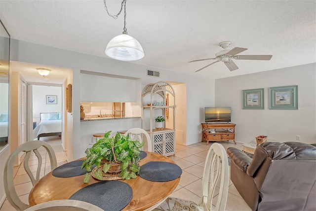 tiled dining room with a textured ceiling and ceiling fan