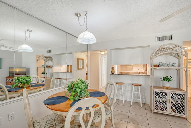 dining area with a textured ceiling and light tile patterned floors