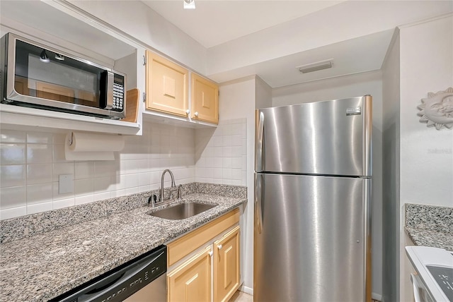 kitchen featuring appliances with stainless steel finishes, sink, backsplash, light stone counters, and light brown cabinets