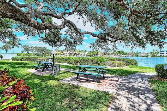 view of property's community with a water view, a patio area, and a yard