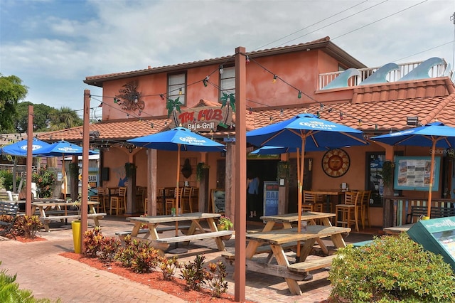 back of house with a balcony, exterior bar, and a patio