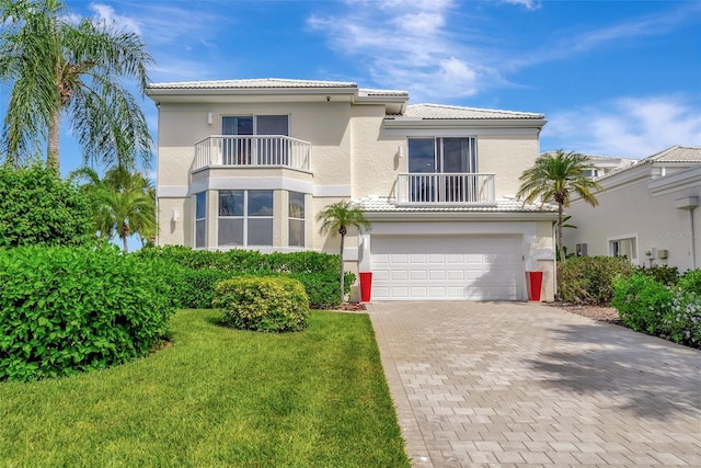 mediterranean / spanish house with a balcony, a garage, and a front lawn