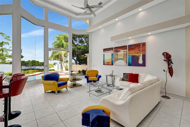 tiled living room with ceiling fan, a healthy amount of sunlight, and a towering ceiling