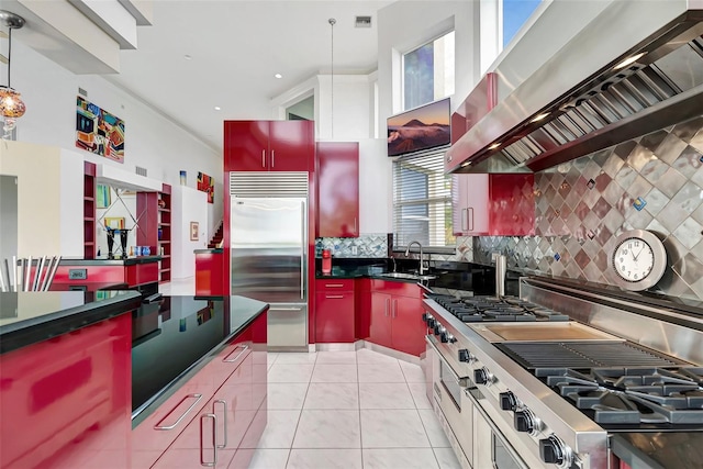 kitchen featuring pendant lighting, premium appliances, tasteful backsplash, and wall chimney range hood