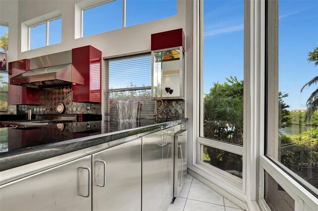 kitchen with light tile patterned flooring, tasteful backsplash, and wall chimney range hood