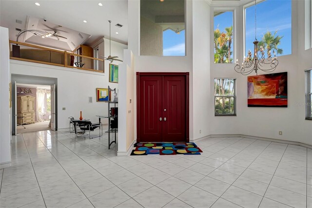 tiled entryway featuring ceiling fan with notable chandelier and a towering ceiling