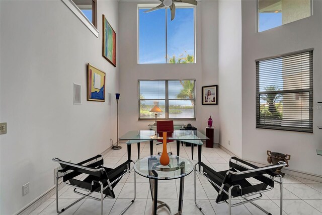 interior space featuring ceiling fan, light tile patterned floors, and a high ceiling