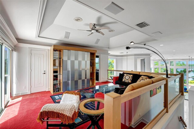 living room with ceiling fan, a raised ceiling, and a wealth of natural light