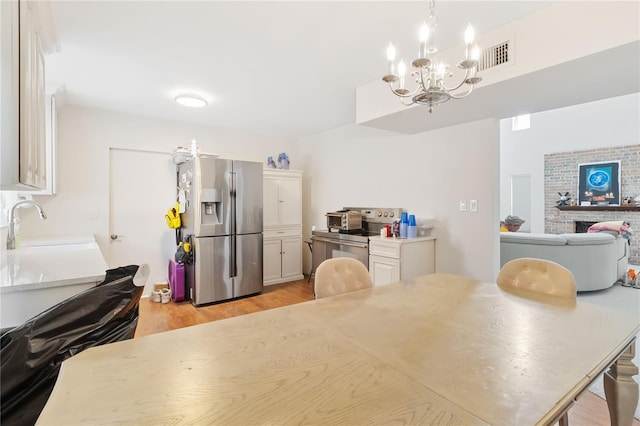 kitchen with sink, appliances with stainless steel finishes, decorative light fixtures, a chandelier, and light wood-type flooring