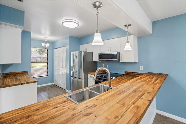 kitchen with appliances with stainless steel finishes, white cabinets, dark hardwood / wood-style floors, hanging light fixtures, and butcher block counters