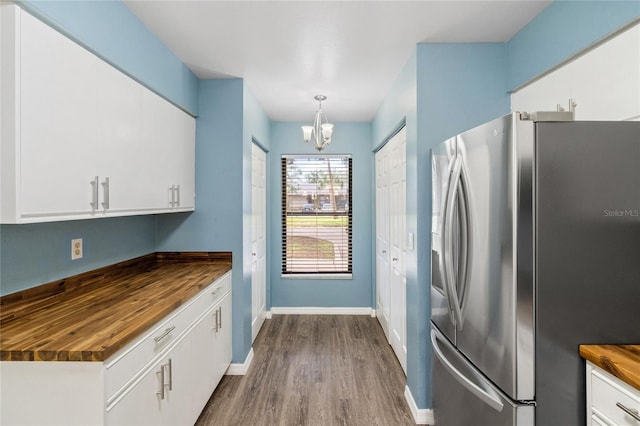 kitchen featuring wood counters, stainless steel refrigerator with ice dispenser, and white cabinetry