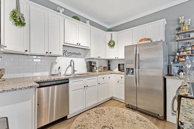 kitchen with backsplash, sink, light stone countertops, appliances with stainless steel finishes, and white cabinetry