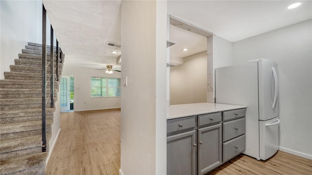 kitchen featuring gray cabinetry, light wood-type flooring, ceiling fan, and white fridge