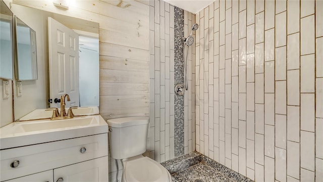 bathroom with vanity, toilet, and a tile shower