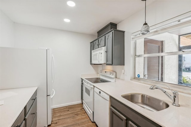 kitchen with sink, gray cabinetry, wood-type flooring, hanging light fixtures, and white appliances