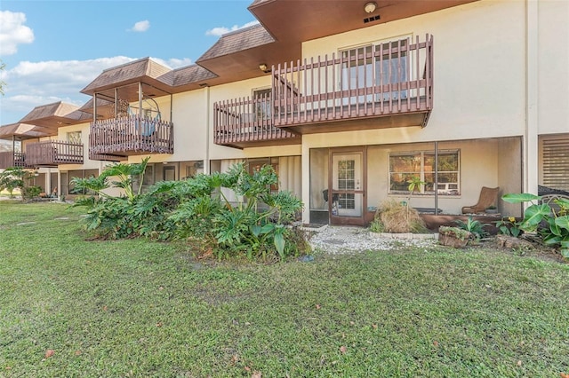 back of house featuring a balcony and a yard