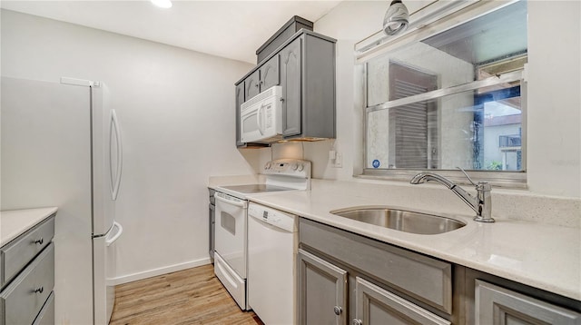 kitchen with light hardwood / wood-style floors, white appliances, gray cabinets, and sink