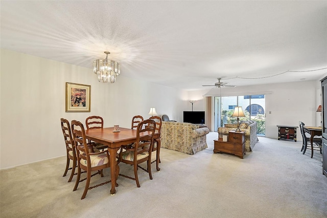 carpeted dining area featuring ceiling fan with notable chandelier