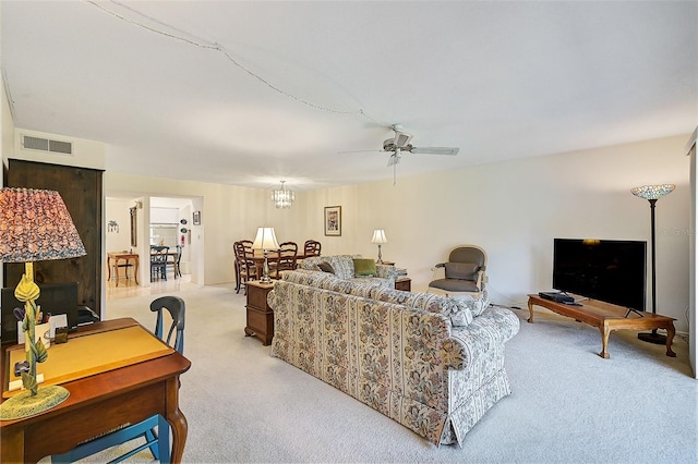 carpeted living room with ceiling fan with notable chandelier