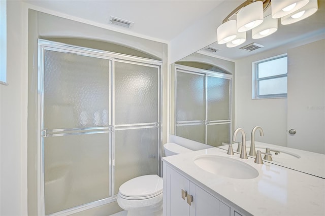 bathroom with a shower with door, vanity, and toilet