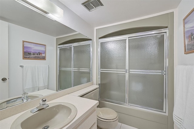 full bathroom featuring shower / bath combination with glass door, tile patterned flooring, vanity, and toilet